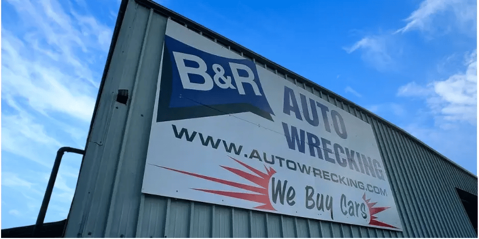  B&R Auto Wrecking sign on a metal building with a blue sky background, advertising car buying. 