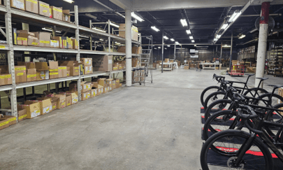 Spacious warehouse with shelving stocked with bicycle parts and accessories.