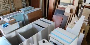 Assorted wooden and laminated panels stacked in a workshop or warehouse, showcasing materials for cabinetry, furniture, or interior design projects.