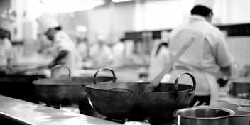 A chef skillfully tossing ingredients in a wok over high flames in a bustling restaurant kitchen, with steam and vibrant colors from vegetables filling the air, capturing the intensity and focus of professional cooking.