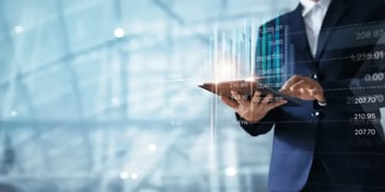 man holding ipad with charts in the background