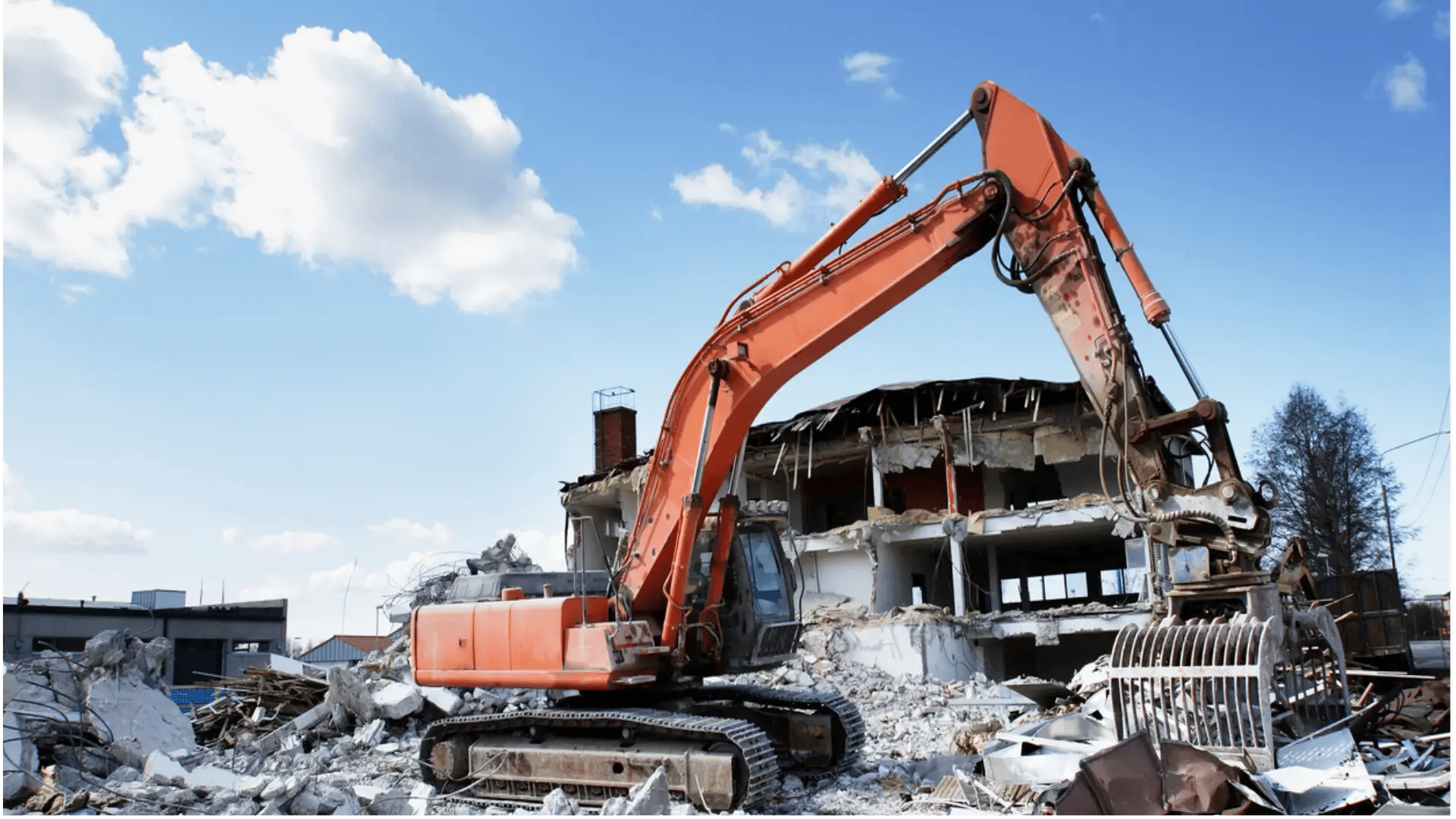  Excavator demolishing a building with rubble in the foreground and clear blue sky in the background. 