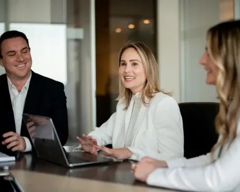 Nina, Jack and Chelsea working together smiling at a boardroom table