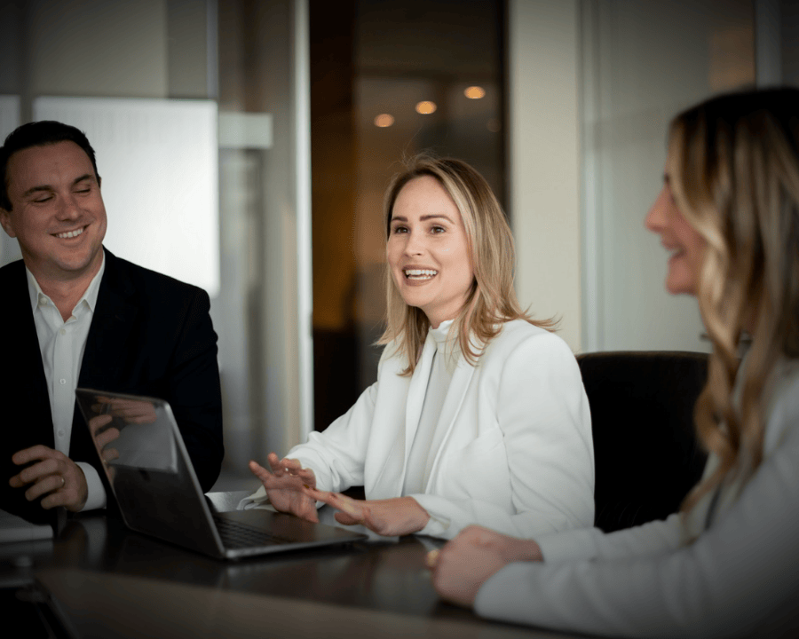 Nina, Jack and Chelsea working together smiling at a boardroom table